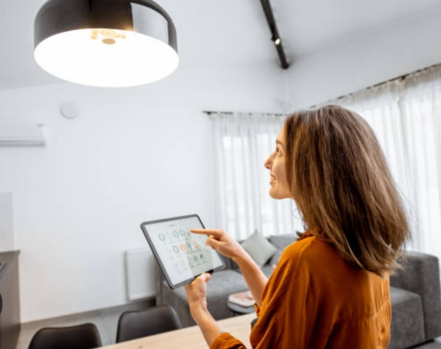 A woman adjusting the brightness of her light in her living room from her smart device.