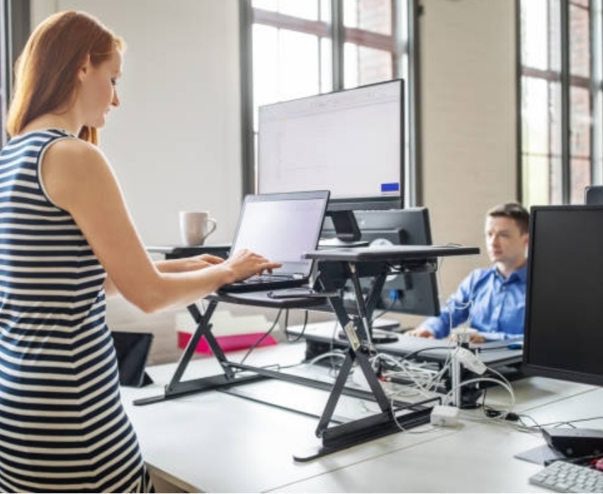 Best Laptop Accessories - Woman wearing a black and white stripe dress using her laptop on laptop stands with a man sitting apposite him