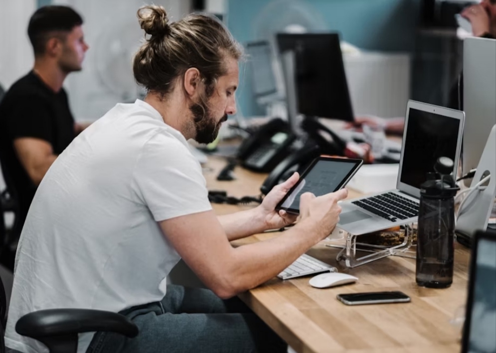 Best Tablets of 2025 - a man using a tablet while on his working desk with a PC in front of him.