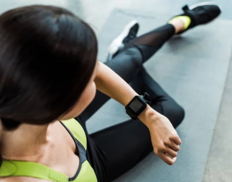 best fitness tracker for 2025 - a woman is doing her workout wearing a fitnerr tracker on he right hand.